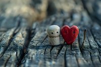 Small wooden figure and red heart on rustic wood surface with shallow depth of field, romantic concept for Valentine's day and love stories.