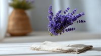 Fresh lavender bouquet floating above linen napkin on white wooden table, with terracotta planter blurred in background.