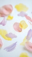 Soft watercolor brush strokes in pastel pink yellow and purple scattered on white paper creating abstract artistic background for creative projects.