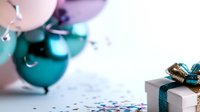 Festive party scene with turquoise and pink balloons, white gift box with glitter bow, and scattered confetti on light background. Celebration and special occasion concept.