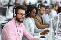 Diverse customer service team working in call center with headsets, providing technical support and assistance to clients.
