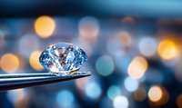 Brilliant diamond held by tweezers against blurred bokeh background of colorful lights, showcasing luxury jewelry craftsmanship.