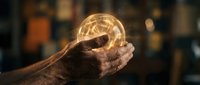 Elderly hands holding glowing light bulb with geometric patterns inside, symbolizing wisdom, innovation and bright ideas in warm atmospheric setting.