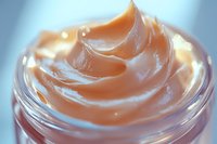 Luxurious swirls of peach-toned cream cosmetic product in glass jar captured in macro photography, highlighting smooth texture and glossy surface for beauty industry use.