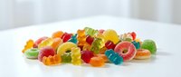 Colorful assorted gummy bears candy scattered on white surface creating vibrant sweet treat display for confectionery and dessert concepts.