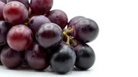 Fresh red grapes cluster with water droplets on white background, isolated for food, health, and nutrition design projects.