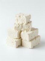 Stacked cubes of crumbly white cheese with visible herb flecks, isolated on neutral background for food photography, culinary design, and recipe content.