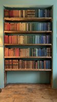 Vintage wooden bookshelf filled with colorful antique books arranged by color gradient from red to blue creating rainbow effect for home library decor.