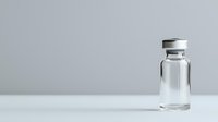 Clear glass medical vial with aluminum cap on white surface against light gray background, minimalist pharmaceutical composition for healthcare concepts.