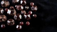 Collection of sparkling brown and reddish gemstones with faceted cuts scattered on dark surface for jewelry design and luxury accessories.