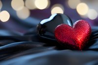 Red glittery heart on dark fabric with warm bokeh lights creating romantic atmosphere for Valentine's Day, love concepts, and relationship themes.