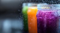 Colorful fresh smoothies in glass jars with condensation droplets on dark background. Vibrant purple, orange and green healthy drinks with bokeh effect.