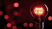 Glowing vintage light bulb with red filament on dark background with bokeh lights. Creative concept for innovation and bright ideas.