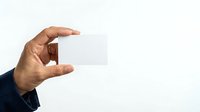 Male hand holding blank white business card isolated on white background for corporate branding and marketing mockup designs.