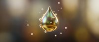 Golden transparent water droplet with rainbow reflections floating against warm blurred background with bokeh lights and sparkles for wellness concepts.