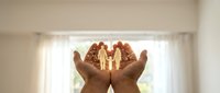 Hands holding glowing miniature house model symbolizing home protection, real estate investment, property insurance and mortgage security concept.