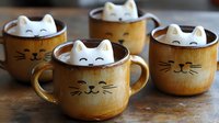Adorable cat-shaped marshmallows floating in hot chocolate served in ceramic mugs with painted cat faces and whiskers for cozy winter drinks.
