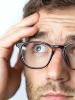 Stressed businessman with glasses holding head in hand showing headache fatigue and work pressure in office environment for mental health concepts.