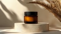 Amber glass cosmetic jar on beige podium with dried pampas grass and natural shadows, minimal product photography for skincare and beauty packaging.