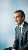 Confident mature Caucasian businessman in gray suit and blue tie smiling optimistically, professional corporate executive portrait for business marketing.
