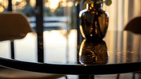 Elegant black marble table with decorative vase silhouette against blurred warm bokeh background creates luxurious atmosphere in modern interior setting.