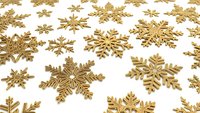 Golden snowflakes scattered on white background creating festive winter holiday pattern for Christmas decorations and seasonal design projects.