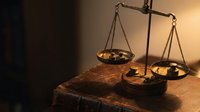 Vintage brass scales of justice on wooden table with warm lighting for legal concepts and law firm presentations.