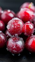 Fresh cranberries covered in frost and water droplets on dark background, extreme macro food photography showing texture and natural patterns.
