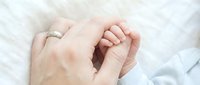 Adult hand holding newborn baby hand, close-up on white fabric background. Symbolizes family bonding, parenting, and new life for maternity, healthcare, and family-related designs.