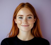 Young redhead woman with freckles and blue eyes wearing black sweater smiling warmly at camera against purple background. Natural beauty portrait showing genuine expression.