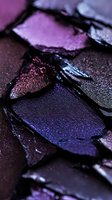 Crushed metallic eyeshadow palette in purple and dark blue shades with shimmer texture, extreme macro shot showing pigment details and sparkle effect.