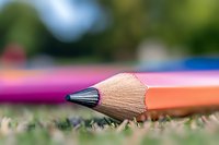 Sharp wooden pencil tip on natural background with soft bokeh effect, extreme close-up macro photography showing detailed wood texture and graphite point.