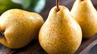 Fresh ripe yellow pears with brown speckles on wooden surface, showcasing natural texture and vibrant color for food photography and healthy eating concepts.