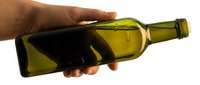 Male hand holding empty olive oil bottle against white background, suitable for culinary, cooking, and food industry marketing materials.