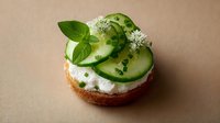 Fresh cucumber slices with herbs and cream cheese on artisan bread slice, healthy appetizer or snack for catering and restaurant menu presentation.