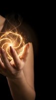 Hands cupping glowing golden energy spiral with magical light effects and sparks against dark background for fantasy and supernatural concepts.