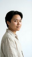 Young Asian man in beige linen shirt smiling confidently against white background. Professional headshot for business, career, lifestyle content.