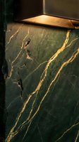 Dark green marble surface with golden veining and warm directional lighting, showcasing luxury stone texture for interior design, architecture, and premium material applications.
