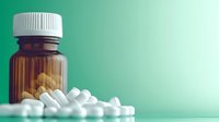Medical pills and tablets spilling from brown prescription bottle on mint green background with soft shadow and copy space for healthcare concept.