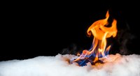 Burning paper documents with orange flames on white snow against black background creating dramatic contrast for fire safety and destruction concepts.