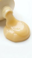 Creamy cosmetic product pouring from jar onto white surface, showcasing smooth texture for skincare, beauty, and cosmetics marketing and packaging design.