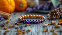 Amethyst crystal bracelet with wooden beads on rustic table surrounded by autumn decorations including pumpkins, pine cones and dried flowers. Natural healing concept.
