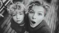 Two surprised children with curly blonde hair expressing shock and amazement in black and white portrait for emotional storytelling and family content.