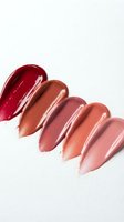Colorful lipstick swatches in red, brown, pink and nude tones arranged in row on white background for cosmetic beauty product testing and makeup palette.