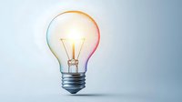 Glowing light bulb with colorful rainbow halo effect against soft blue background, symbolizing creative innovation and bright ideas for business concepts.