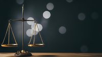 Golden brass scales of justice on wooden surface with soft bokeh lights background for legal and law firm presentations.
