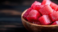 Fresh juicy watermelon cubes in wooden bowl against dark background, perfect for summer food concepts and healthy eating designs.