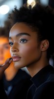 Young African American woman with natural curly hair in profile view against blurred background, showcasing natural beauty and confidence in fashion portrait style.