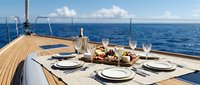 Elegant dining setup on luxury yacht deck with place settings, wine bottle, and gourmet food spread overlooking open ocean, suitable for travel, hospitality, and lifestyle marketing.