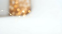 Soft blurred golden bokeh lights creating warm ambient glow on clean white background for holiday decorations and festive seasonal design projects.